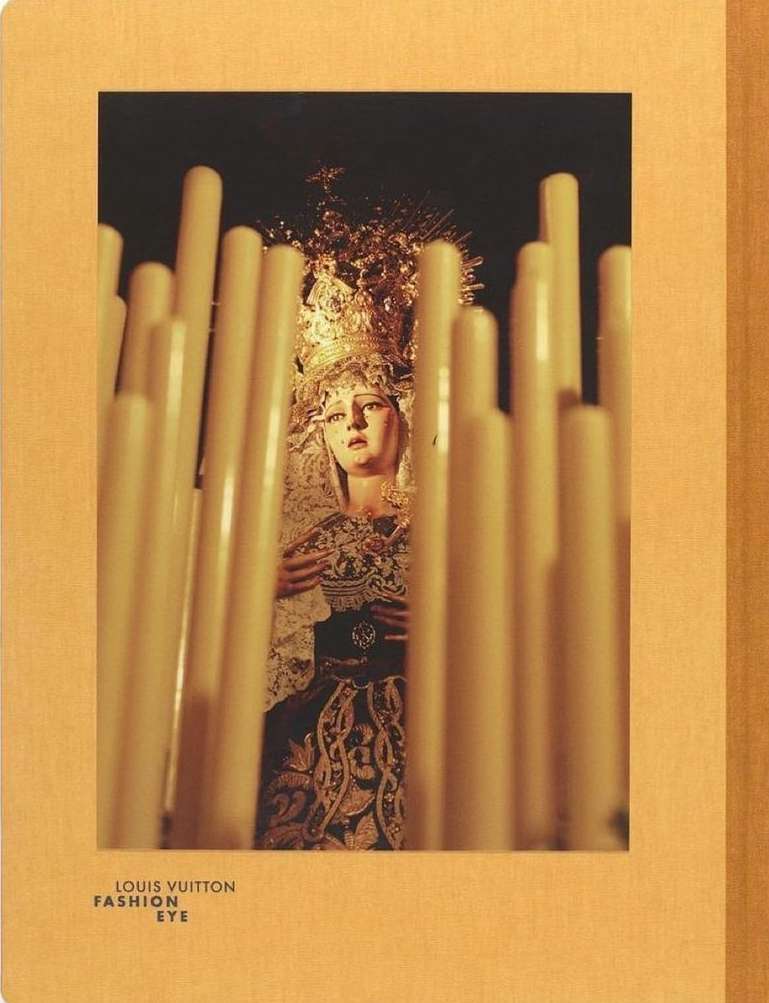 Statue of a religious figure surrounded by many candles, captured in a medium shot with a focus on the statue and candles.