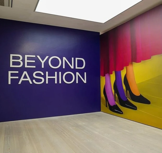 Interior shot of a purple wall with the text 'Beyond Fashion' and a fashion advertisement featuring legs in colorful tights.
