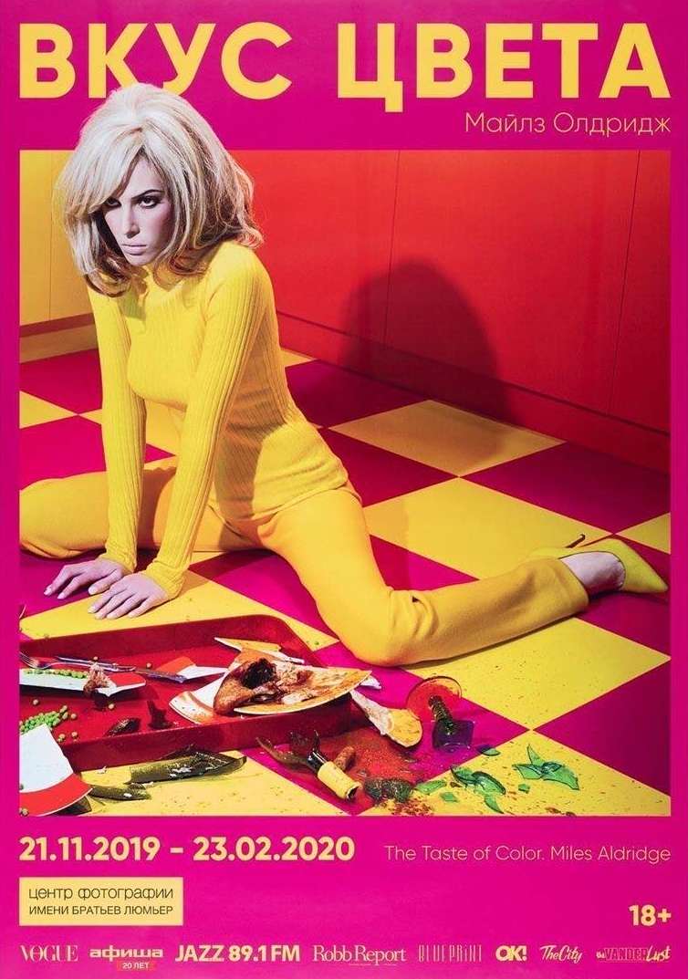 Blonde woman in yellow outfit reclines on a geometric floor in a Miles Aldridge art-photography poster featuring 'The Taste of Color' exhibition.