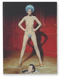 A nude female model with a blue afro and orange mules stands over a head emerging from a hole in the floor against red wood-paneled walls.