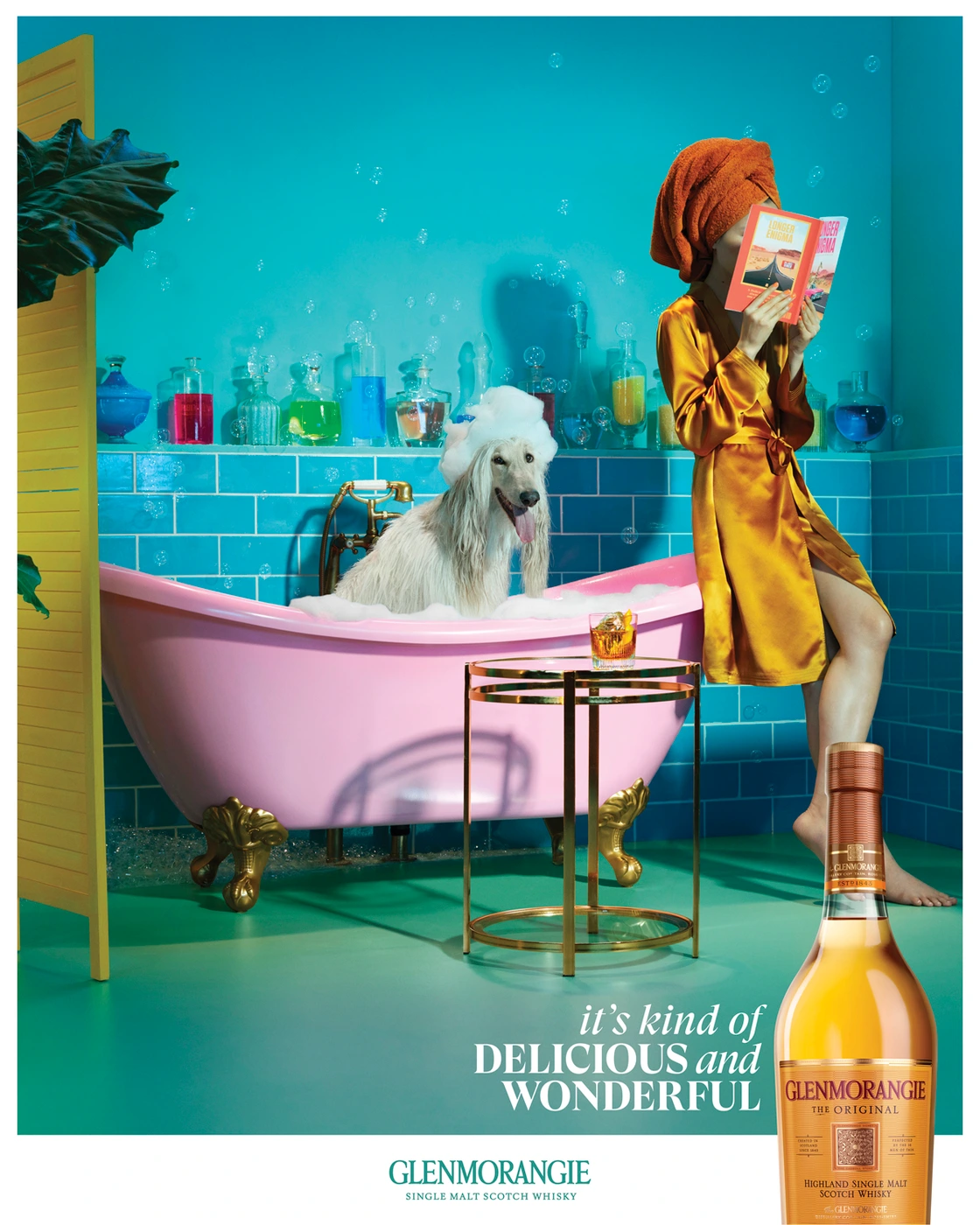 Woman in satin robe and orange hair wrap reading a book in a bathroom with a dog in a pink bathtub, photographed by Miles Aldridge