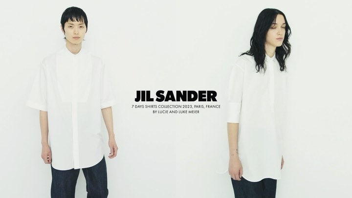 Fashion editorial shot of two slender models wearing oversized white shirts and dark jeans against a stark white backdrop for JIL SANDER 2023.