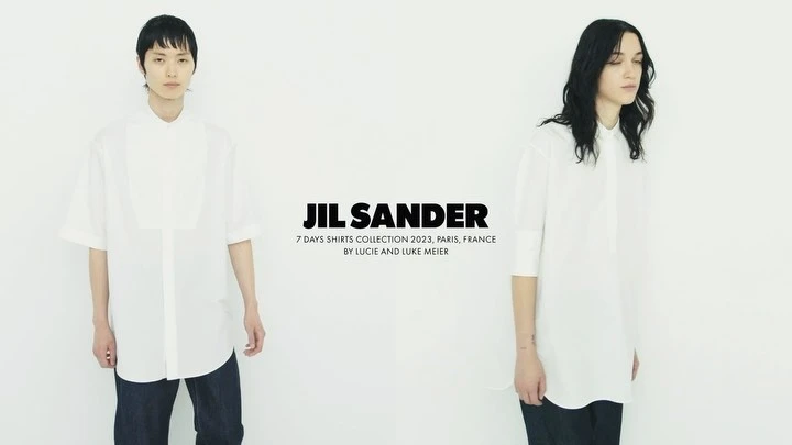 Fashion editorial shot of two slender models wearing oversized white shirts and dark jeans against a stark white backdrop for JIL SANDER 2023.
