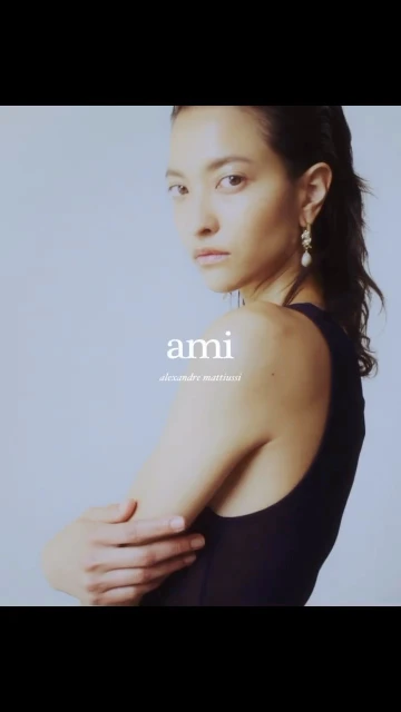 Portrait of a woman with pearl earrings posing in a sleeveless top against a light background with the text 'ami alexandre mattiussi'.