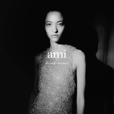 Black and white portrait of a model wearing a sequined top with dramatic low-key lighting and a dark background.