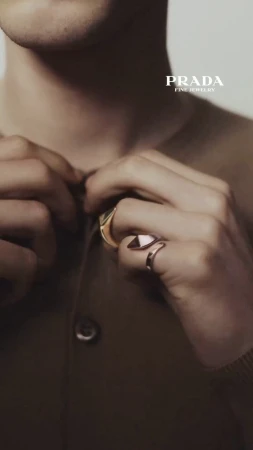 Close-up shot of a person wearing gold rings from Prada's fine jewelry collection, showcasing a minimalist and elegant aesthetic.