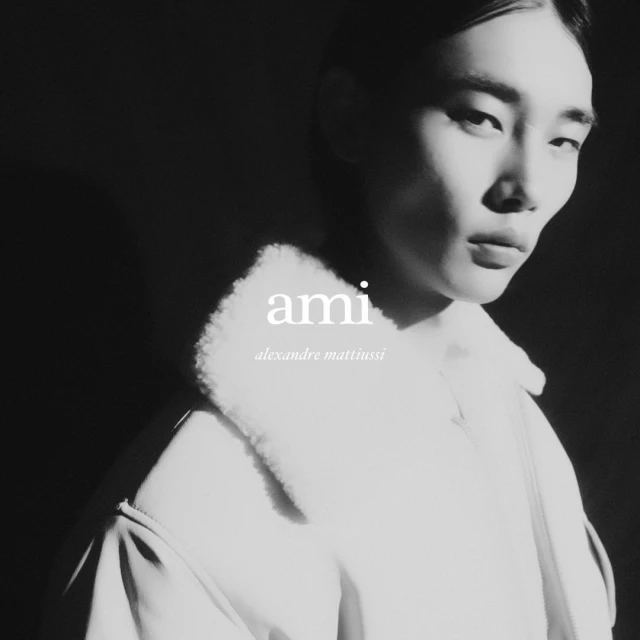 Portrait of an Asian male model with fair skin wearing a wool coat with white faux fur collar, black and white fashion advertising