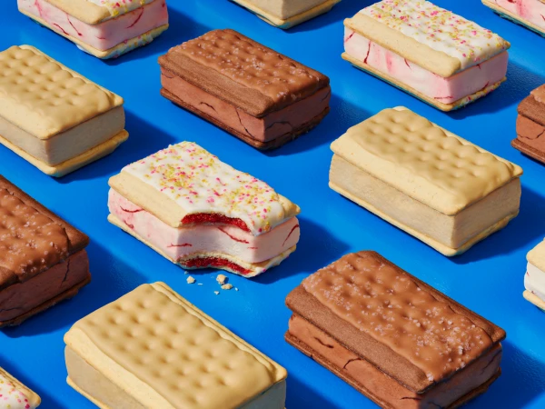 Arrangement of ice cream sandwiches with vanilla, chocolate, and strawberry flavors on a blue background with a studio lighting.
