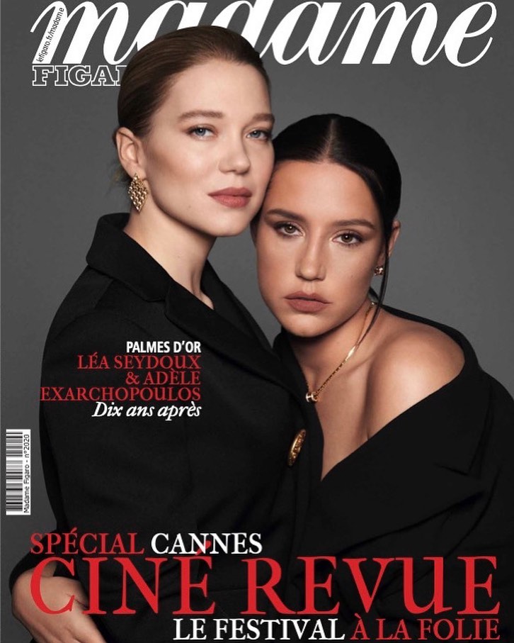 Magazine cover featuring two adult women, Léa Seydoux and Adèle Exarchopoulos, in black clothing, against a solid grey backdrop.