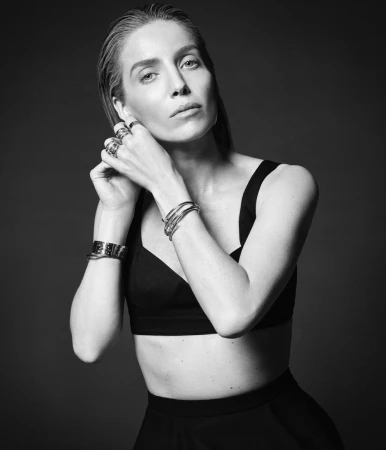Monochrome portrait of a woman wearing jewellery and a black top against a dark studio background