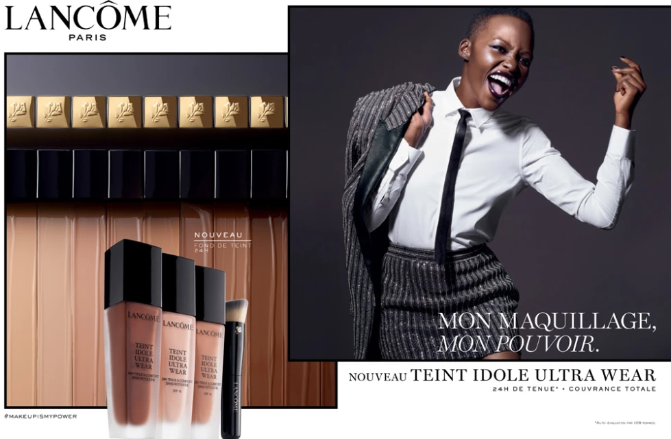 Cosmetic ad featuring a Black woman in a suit alongside Lancôme Teint Idole Ultra Wear foundation and makeup brush products.