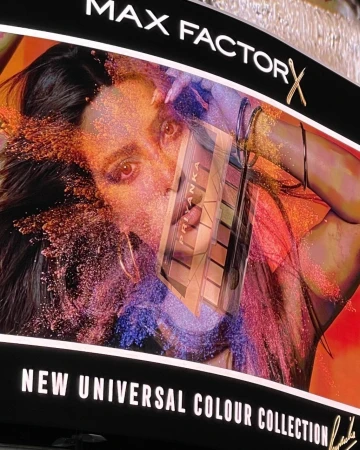 Cosmetics advertisement featuring a woman's face, makeup palette, and colorful powder explosion for Max Factor's Universal Colour Collection.