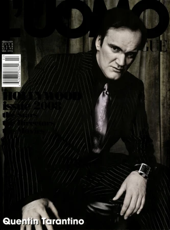 An eye-level, medium shot of an adult male fashion model in a blue suit posing against a light-blue studio backdrop.