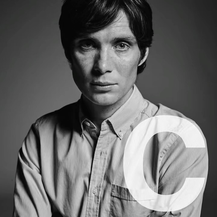 Black and white portrait of Cillian Murphy wearing a striped button-down shirt, captured in a close-up shot against a grey background.