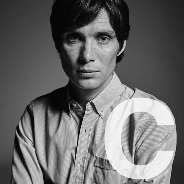 Black and white portrait of Cillian Murphy wearing a striped button-down shirt, captured in a close-up shot against a grey background.