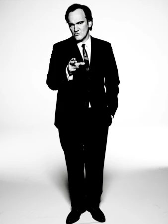 Portrait of a contemplative adult male with short brown hair, wearing a dark jacket and white t-shirt against a blurred background.