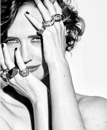 Close-up monochrome portrait of a woman wearing statement silver rings on both hands framing her face