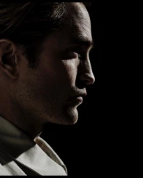 Profile portrait of a man in deep shadow with light highlighting the side of his face, photographed by Tom Munro.