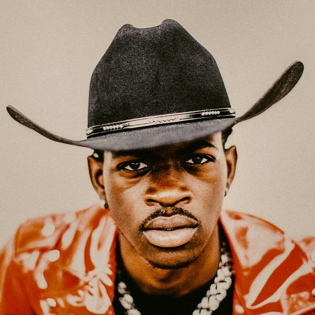 Portrait of a Black man wearing a black cowboy hat and a red patterned jacket by Christaan Felber