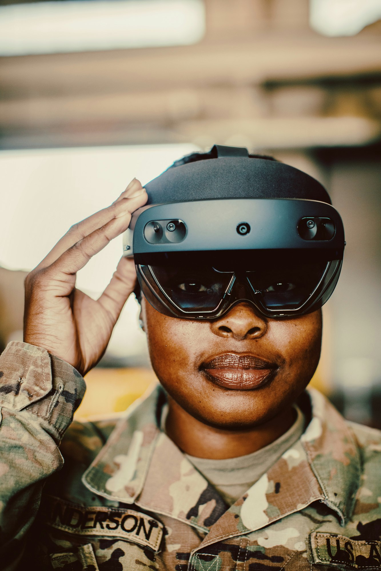 Woman in military uniform wears augmented reality headset, saluting indoors. Close-up shot with diffused lighting, focusing on technology.