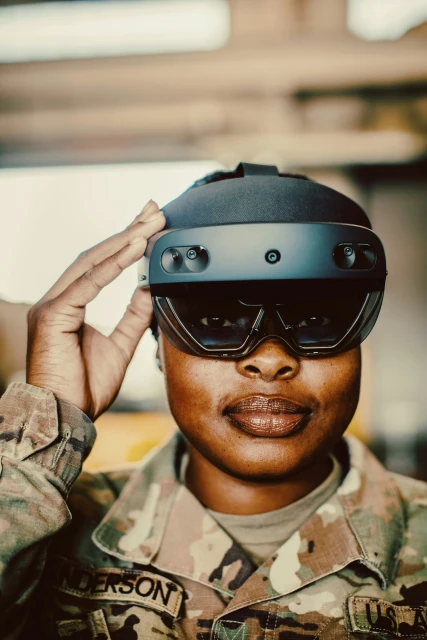 Woman in military uniform wears augmented reality headset, saluting indoors. Close-up shot with diffused lighting, focusing on technology.