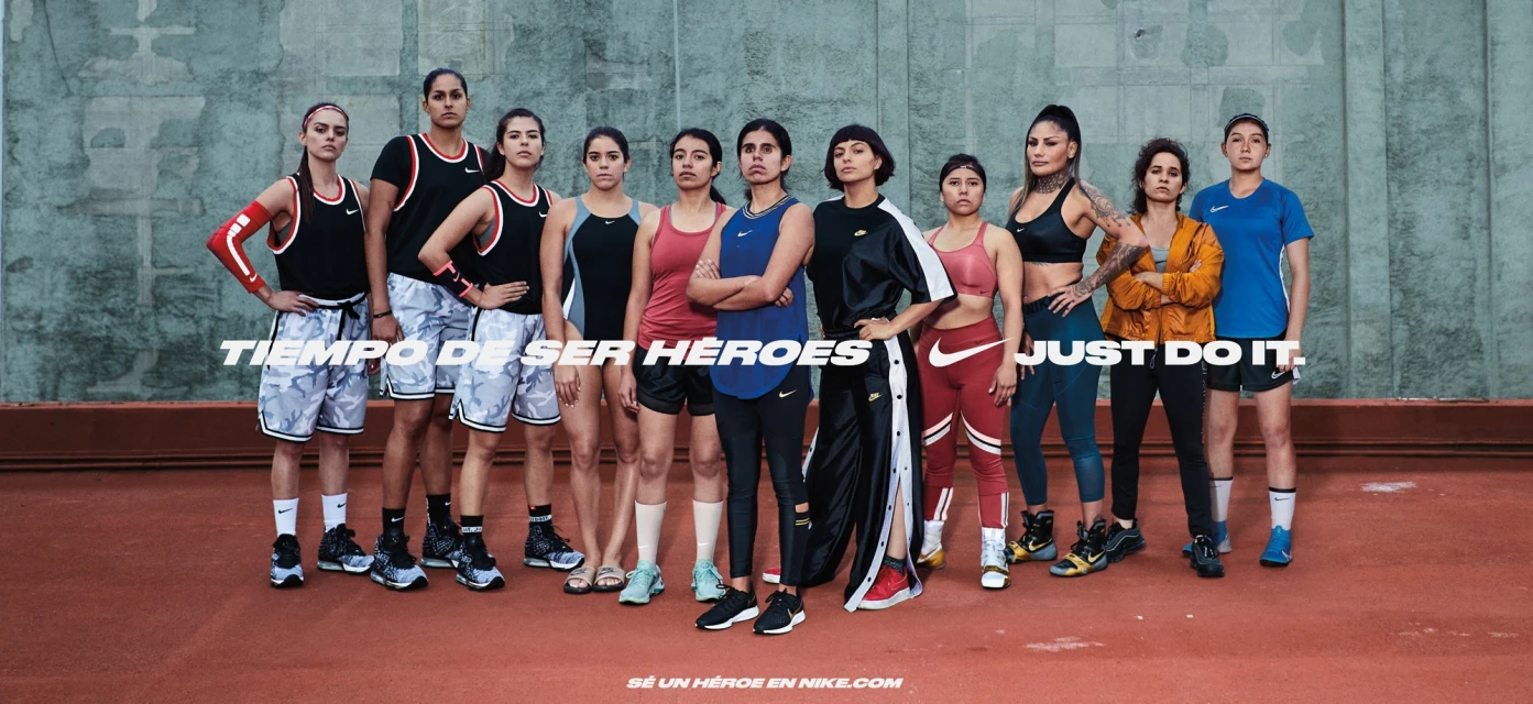 Group of diverse women athletes in sportswear standing together in front of a textured wall, promoting the Nike brand with motivational text.