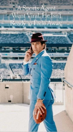 Man in pinstripe suit with football and phone poses in stadium concourse, wearing burgundy fedora for sports lifestyle imagery.