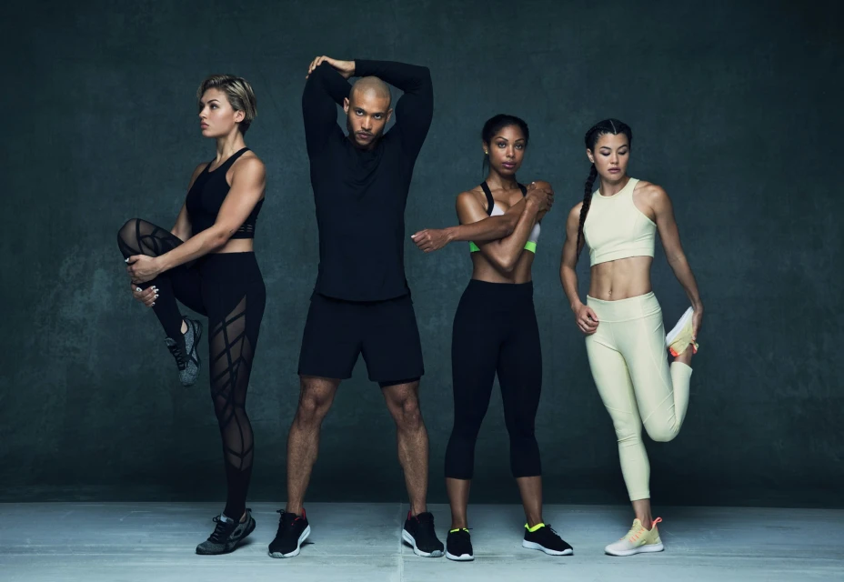 Four diverse fitness models strike dynamic stretching poses in athletic wear against a dark backdrop, promoting health and wellness.