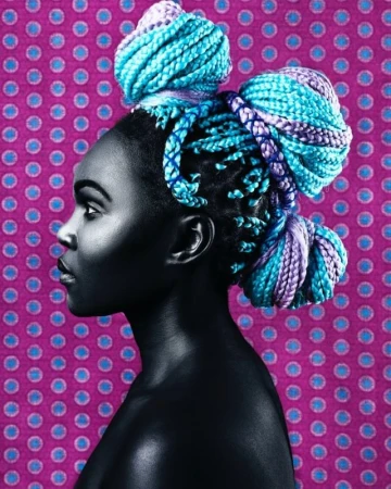 Profile of a Black woman with blue and purple braided hair styled in buns, against a purple polka dot background.
