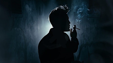 Silhouette of a person smoking a cigarette against a dark background with smoke, creating a moody and atmospheric visual.