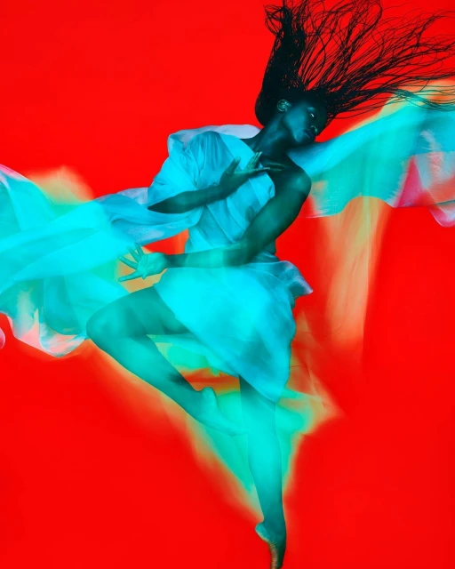 Artistic full-body portrait of a Black woman dancing with flowing white fabric against a vivid red background, showcasing movement and elegance.