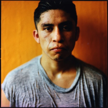 Portrait of a man in a grey t-shirt against a vibrant orange wall