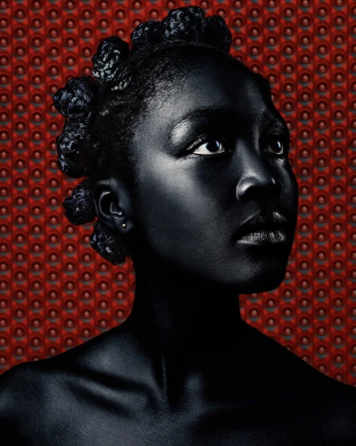 Portrait of a stylish young Black woman in a high-fashion studio setting with dark skin, hair styled in knots, and a patterned backdrop.