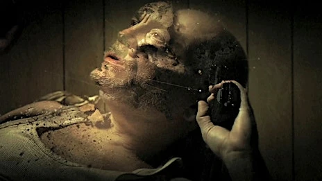 Disturbing close-up of an adult male's face with discoloration and an object in hand, set against a dimly lit, textured background.
