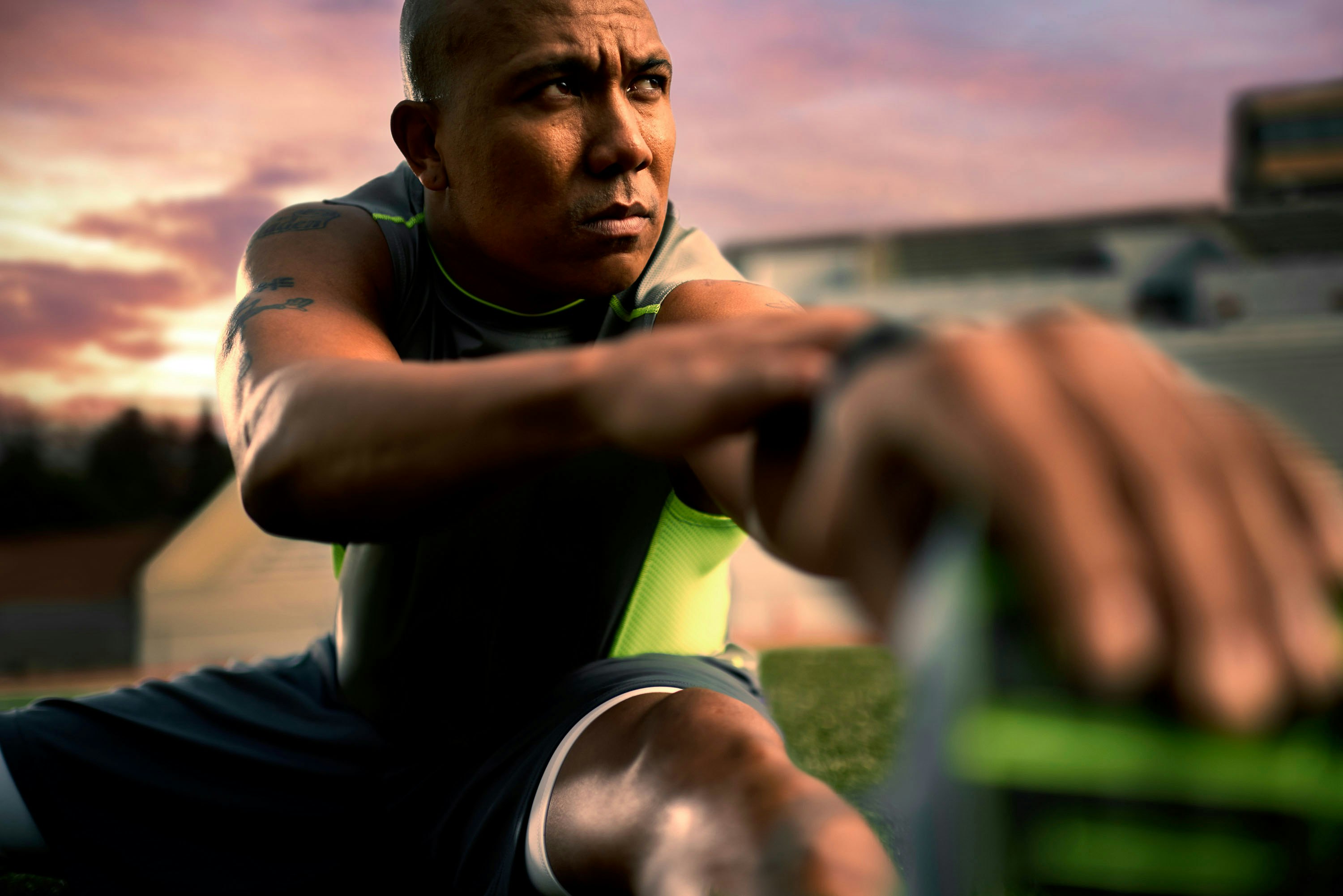 Man stretching outdoors in athletic wear with a dramatic sunset sky in the background by photographer Sandro