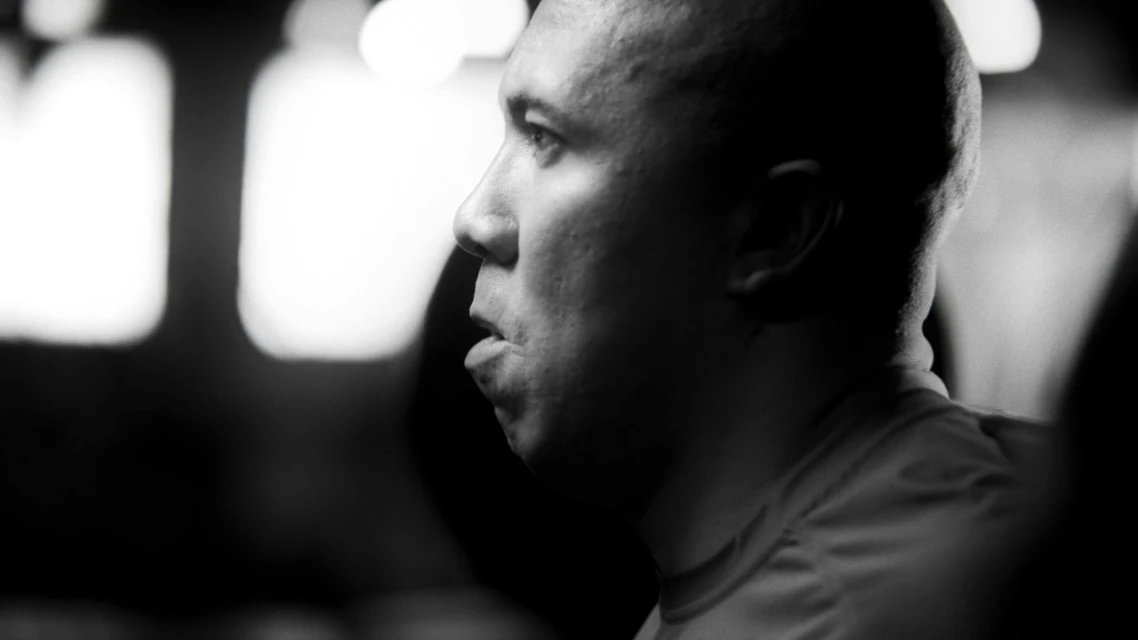 Monochrome portrait of a light-skinned adult male in a close-up profile with blurred lights in the background, focusing on facial details.