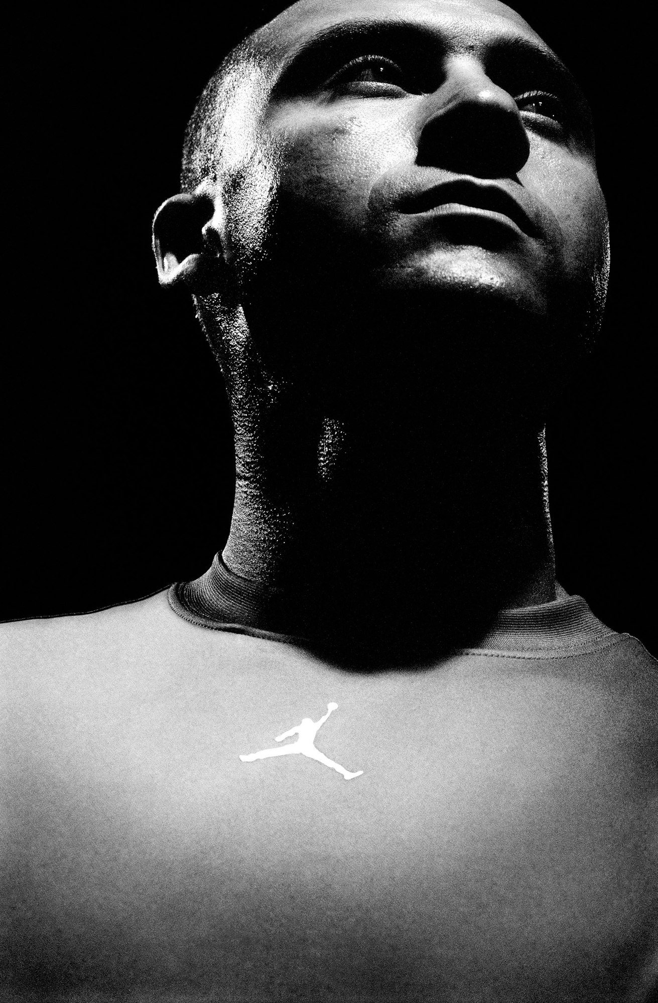 Low angle monochrome portrait of a bald man wearing an athletic t-shirt with a white jumping man logo in Chicago.
