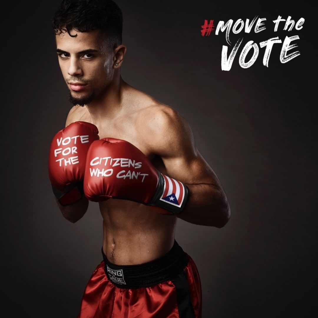 A male boxer in red shorts and gloves with a message stands against a gray background in a studio shot, advocating for voting rights.
