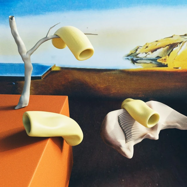 Surreal still life of floating, pale yellow, abstract shapes against a backdrop of an ocean landscape with light and shadow.