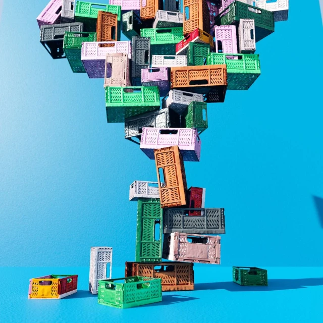 Colorful arrangement of stacked and scattered plastic storage crates against a vivid blue background in a studio setting.