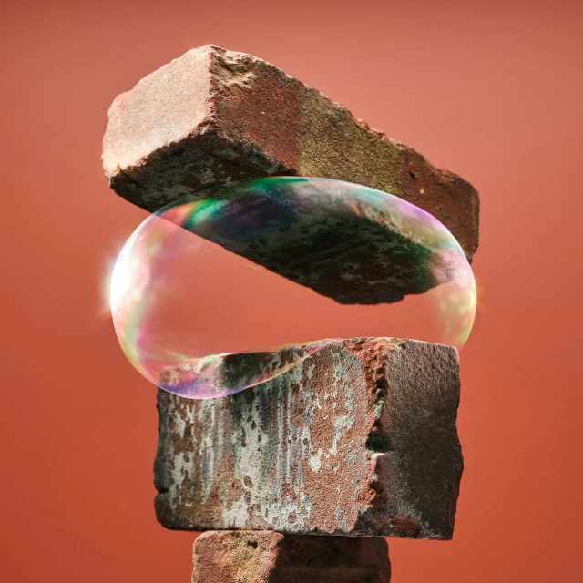 Abstract still life with a soap bubble between layered textured bricks against a reddish-brown background. Abstract art concept.