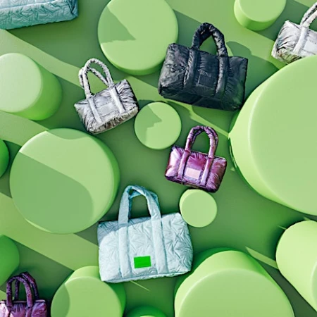 Overhead studio shot of colorful quilted tote bags arranged on geometric green cylinders and platforms