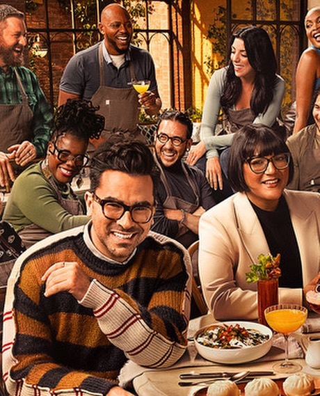 Group of diverse chefs and culinary hosts smiling around a restaurant table with drinks and dishes by Art Streiber