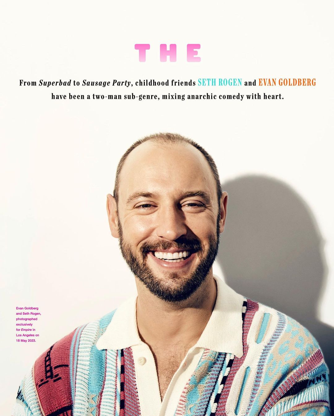 Portrait of a smiling white man wearing a patterned knit polo shirt against a plain white studio background.