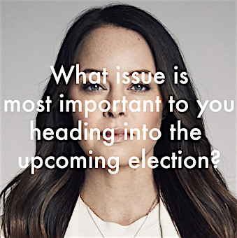 Portrait of a woman with long, wavy brown hair wearing a silver necklace, against a neutral backdrop with overlayed election text.
