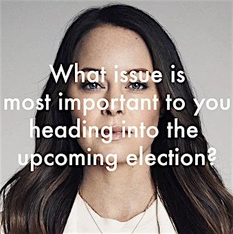 Portrait of a woman with long, wavy brown hair wearing a silver necklace, against a neutral backdrop with overlayed election text.