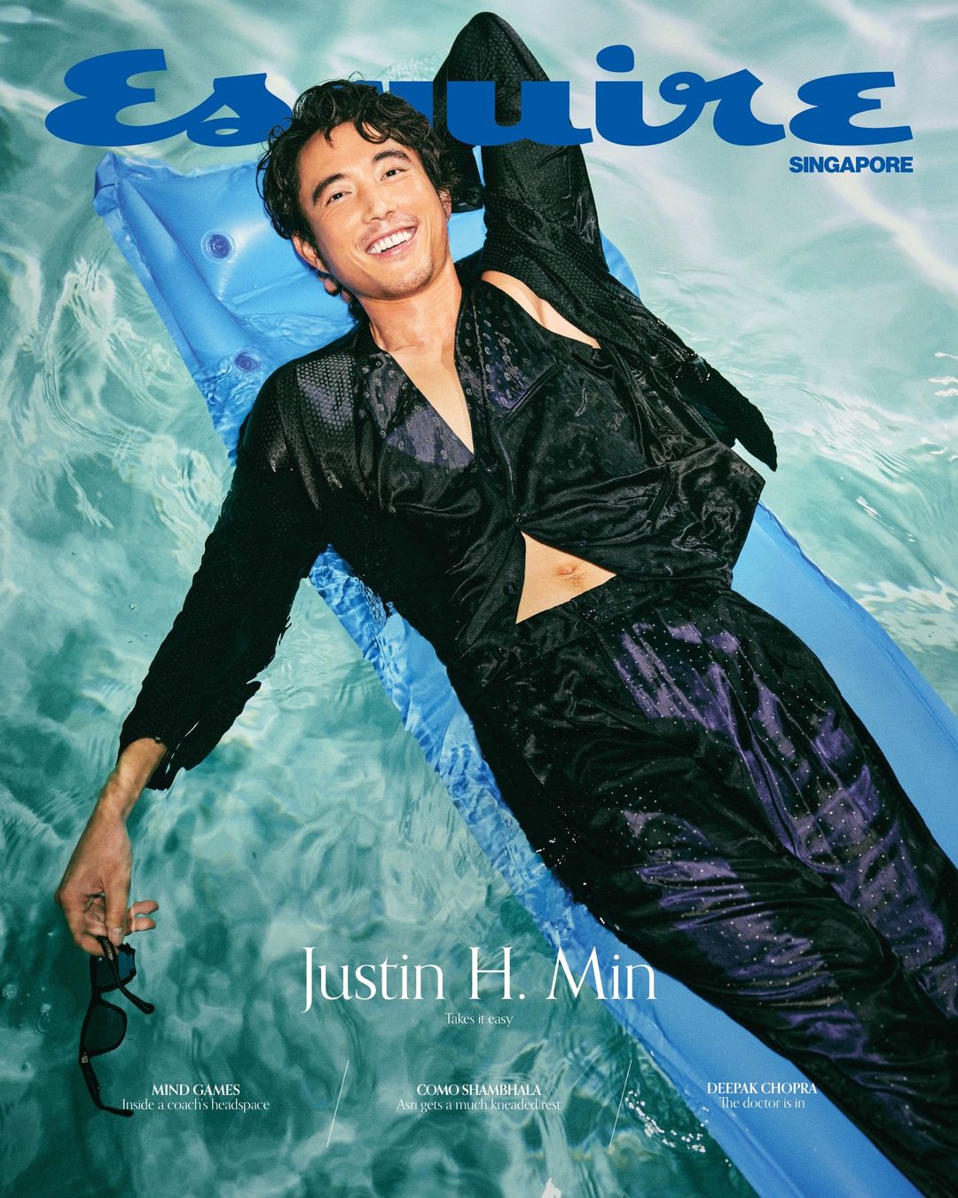 Esquire Singapore magazine cover features Justin H. Min lying on an inflatable raft in a pool, wearing a black patterned outfit and sunglasses.