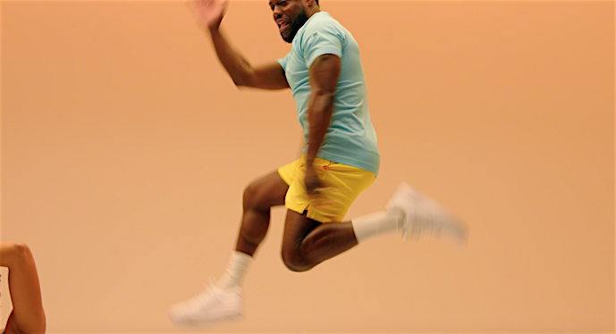 Athletic adult male in motion wearing sportswear in studio with solid neutral background; jumping, mid-air.