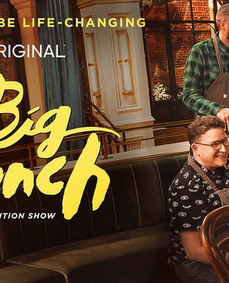 Two men in aprons are seated indoors, likely for a food or cooking show called 'Big Brunch' with yellow text and a windowed building backdrop.