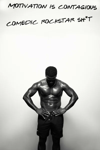 Black and white portrait of a muscular man standing shirtless with hands on waist against a plain white studio wall.